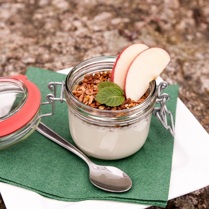 Joghurt mit Granola und zwei Apfelspalten in einem Einmachglas