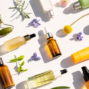 Die Bildkomposition zeigt verschiedene Beauty-Produkte, Pflanzenextrakte und einen Jade-Roller, die für natürliche Hautpflege und Selfcare stehen.