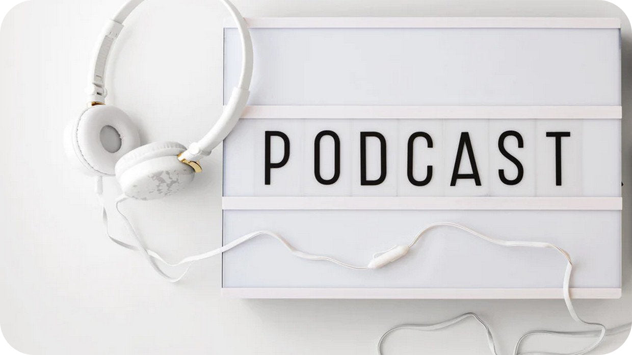 Kopfhörer vor einer Tafel mit dem Schriftzug Podcast