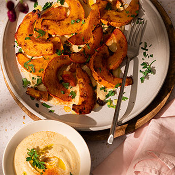 Gebackene Kürbisspalten auf samtigem Bohnen-Hummus
