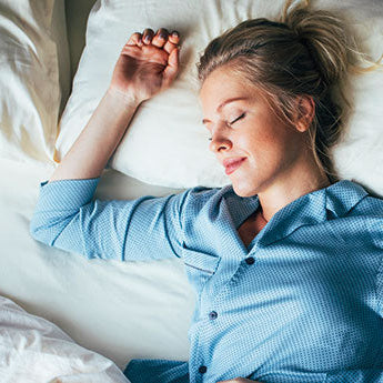 Schlafende Frau in Blauem Pyjama in weißem Bettzeug