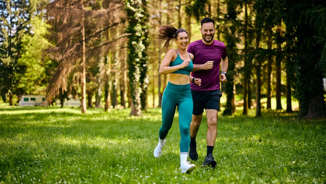 Mann und Frau joggen gut gelaunt im Wald