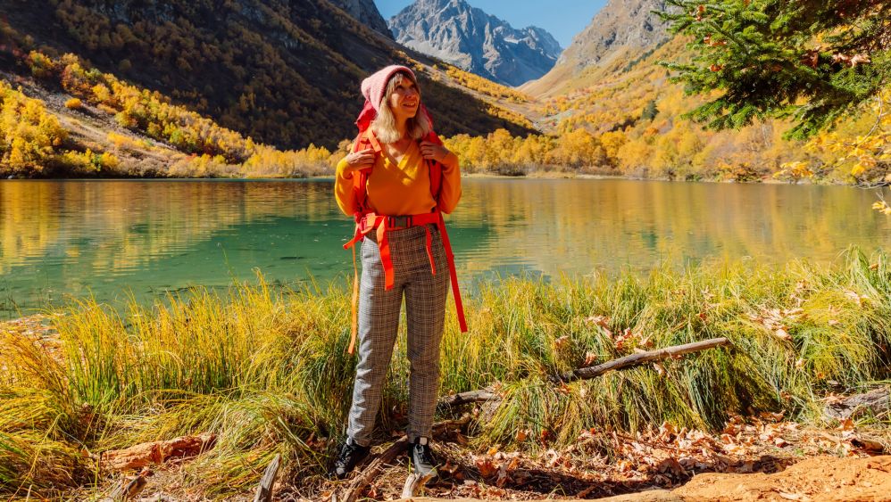 Junge Frau mit Mütze und Rucksack vor herbstlichen Bergpanorama