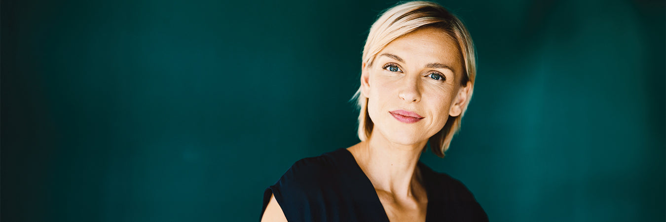 Blonde Frau mit dunkelblauer Bluse von dunkelgrünem Hintergrund