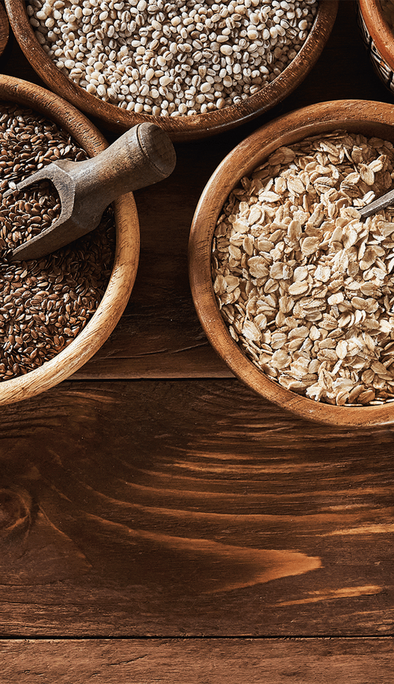 Getreide, Samen und Saaten in Schalen auf Holzplatte