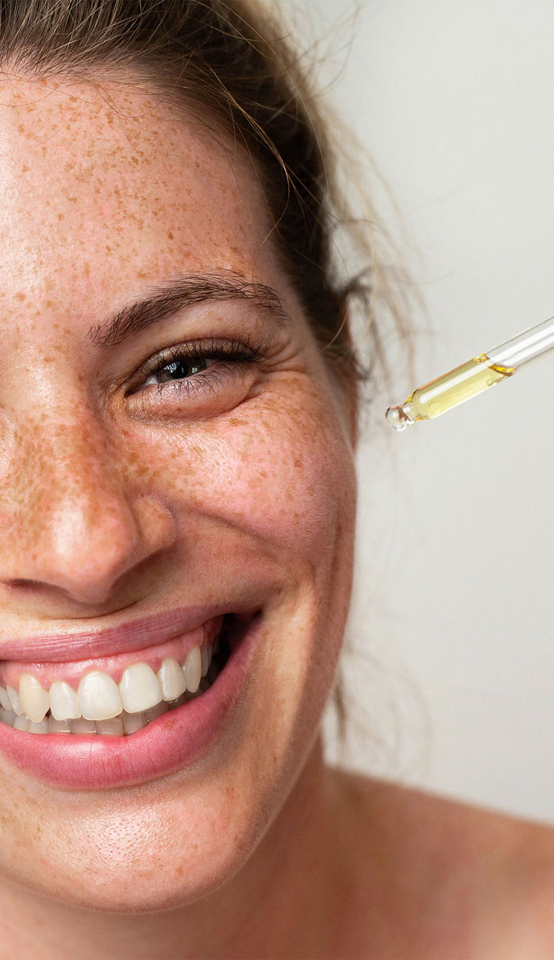 Strahlendes Gesicht einer jungen Frau mit Pipette mit Serum in der Hand
