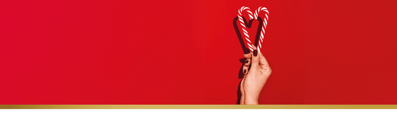 Frauenhand hält zwei Zuckerstangen zu einem Herz