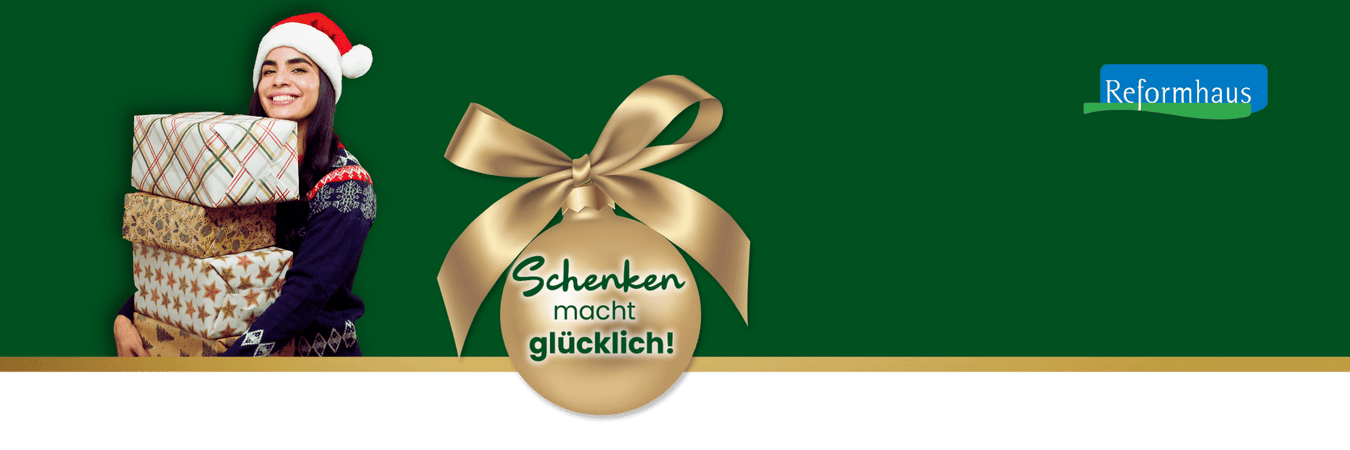 Junge Frau mit Weihnachtsmütze und vier Geschenken im Arm lächelt freundlich – unser Motto "Schenken macht glücklich!