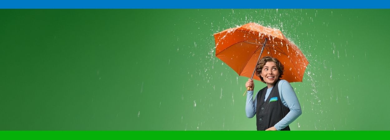 Reformhaus Beraterin mit orangen Regenschirm im Regen